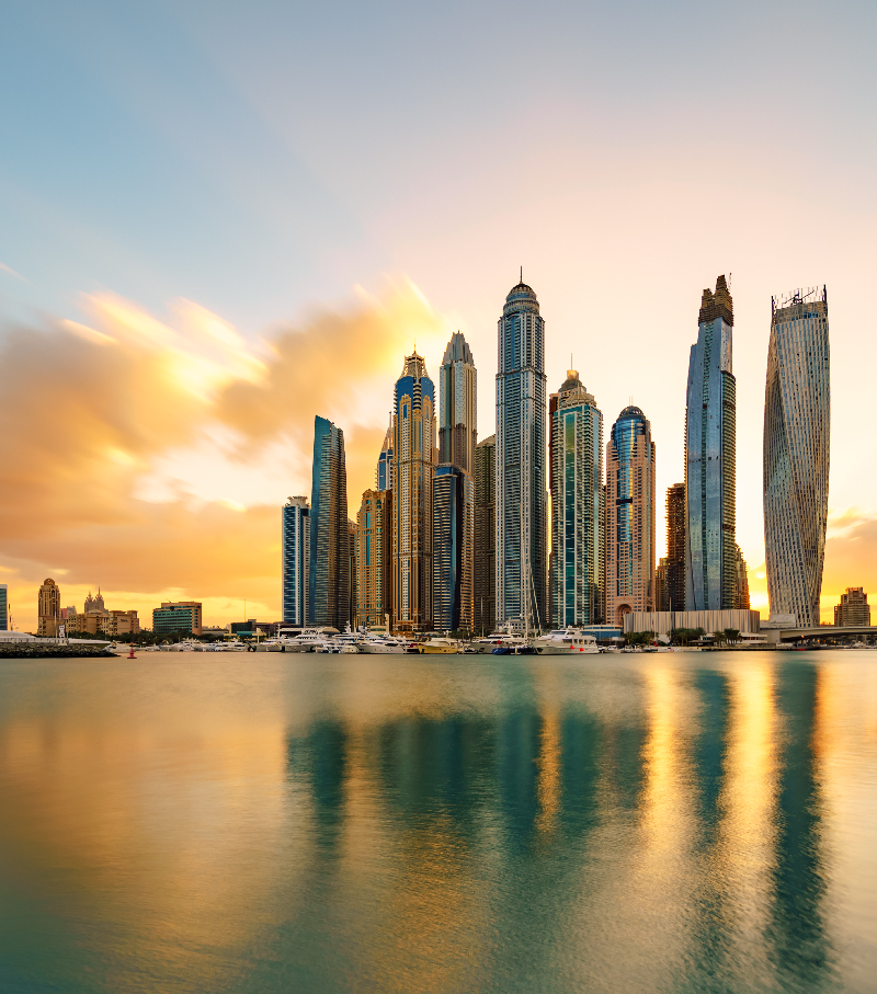 Stunning long-exposure shot of the Dubai Marina skyline and its towering skyscrapers at sunset, with luxury yachts moored below. This embodies high-end urban travel and architectural excellence in the Middle East.